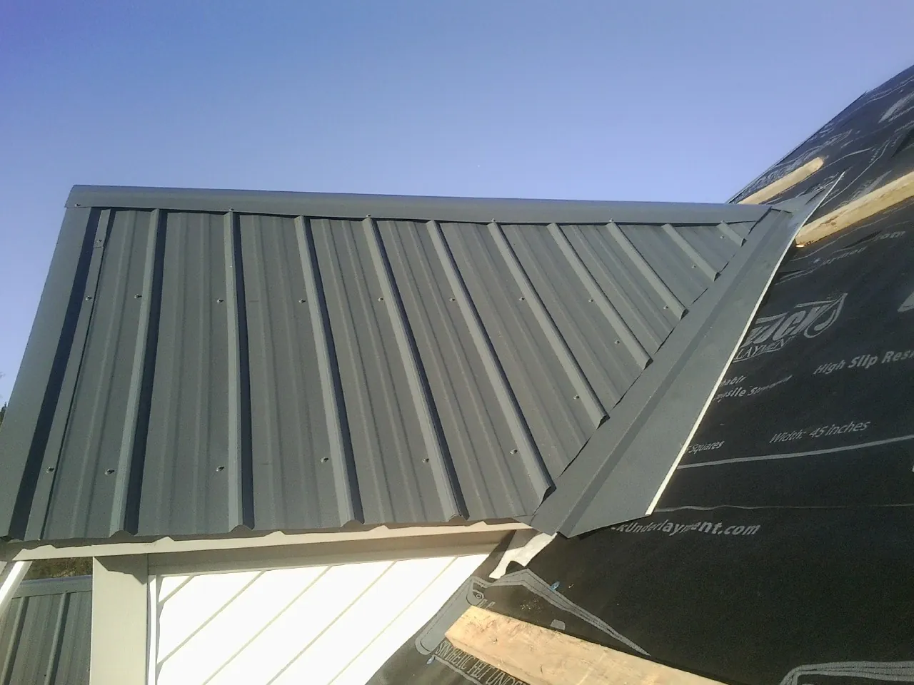 Gray metal roof panels going on over a garage gable in Clara City