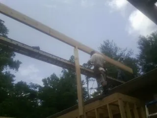 Carpenter setting a ridge beam over a new addition frame — Ice Dam Removal by Roofing Brothers in Clara City