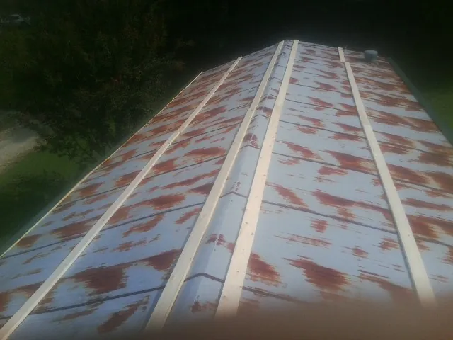 Rusted metal roof panels with new wood purlins before replacement — Storm Damage Roof Repair in Clara City by Roofing Brothers