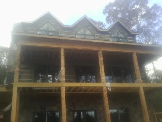 Dormers and porch framing on a large log home under construction — Roof Coating work by our crew in Clara City