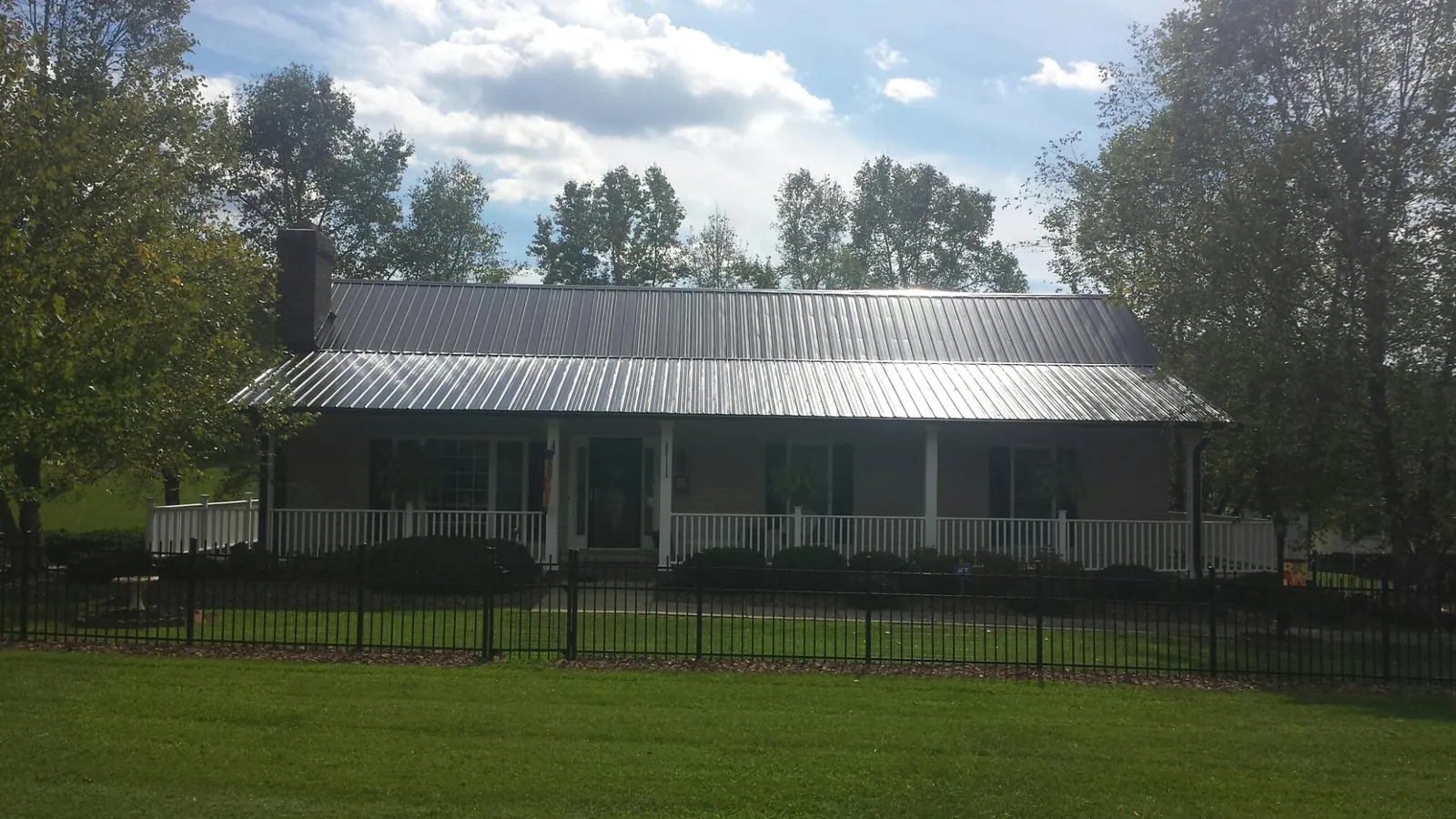 Gray metal roof on a brick ranch with a full width front porch — Gutter Guard Installation work by our crew in Clara City