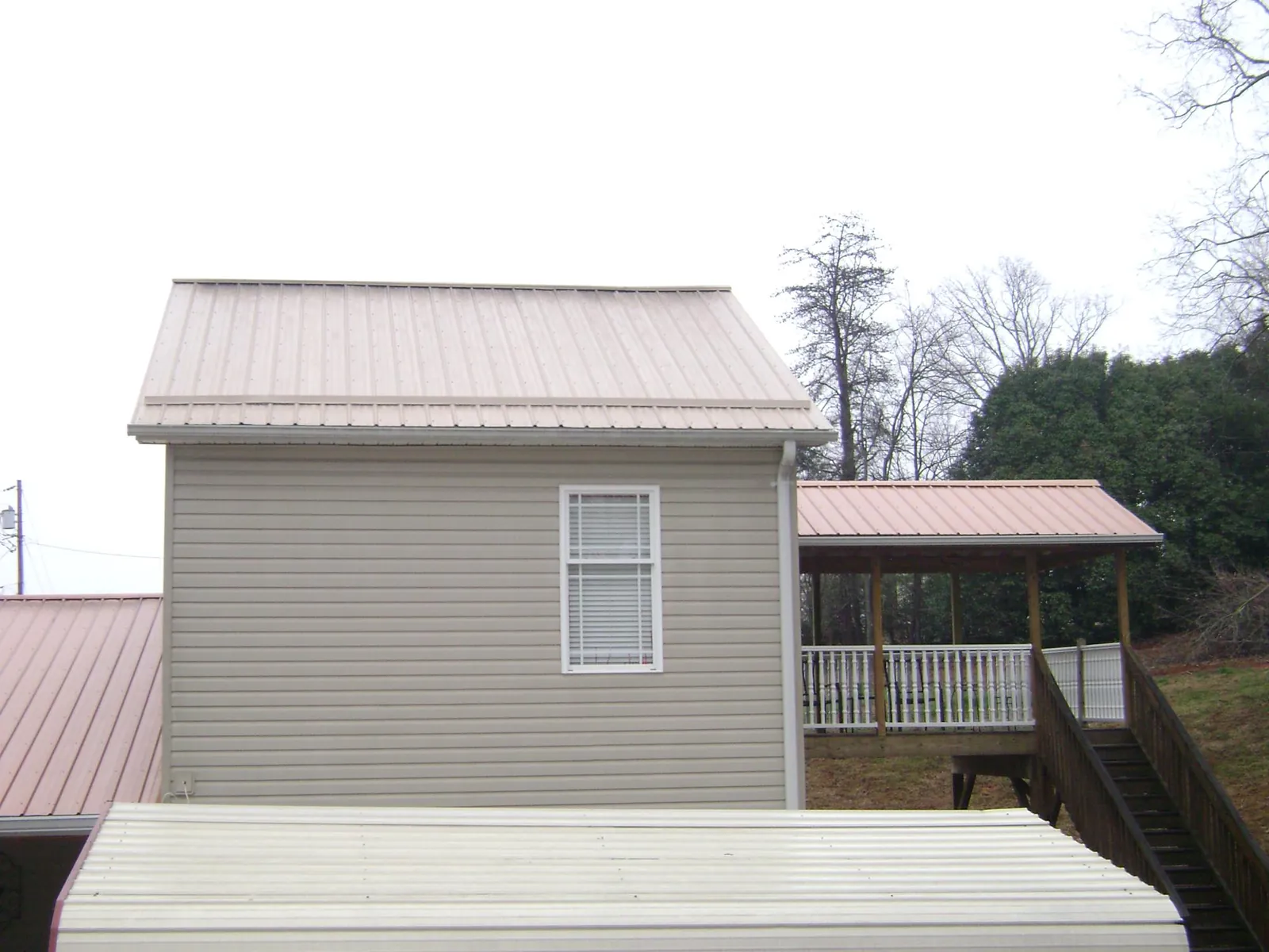 Tan metal roofs on a two story addition and attached porch, from a Roof Replacement job in Clara City